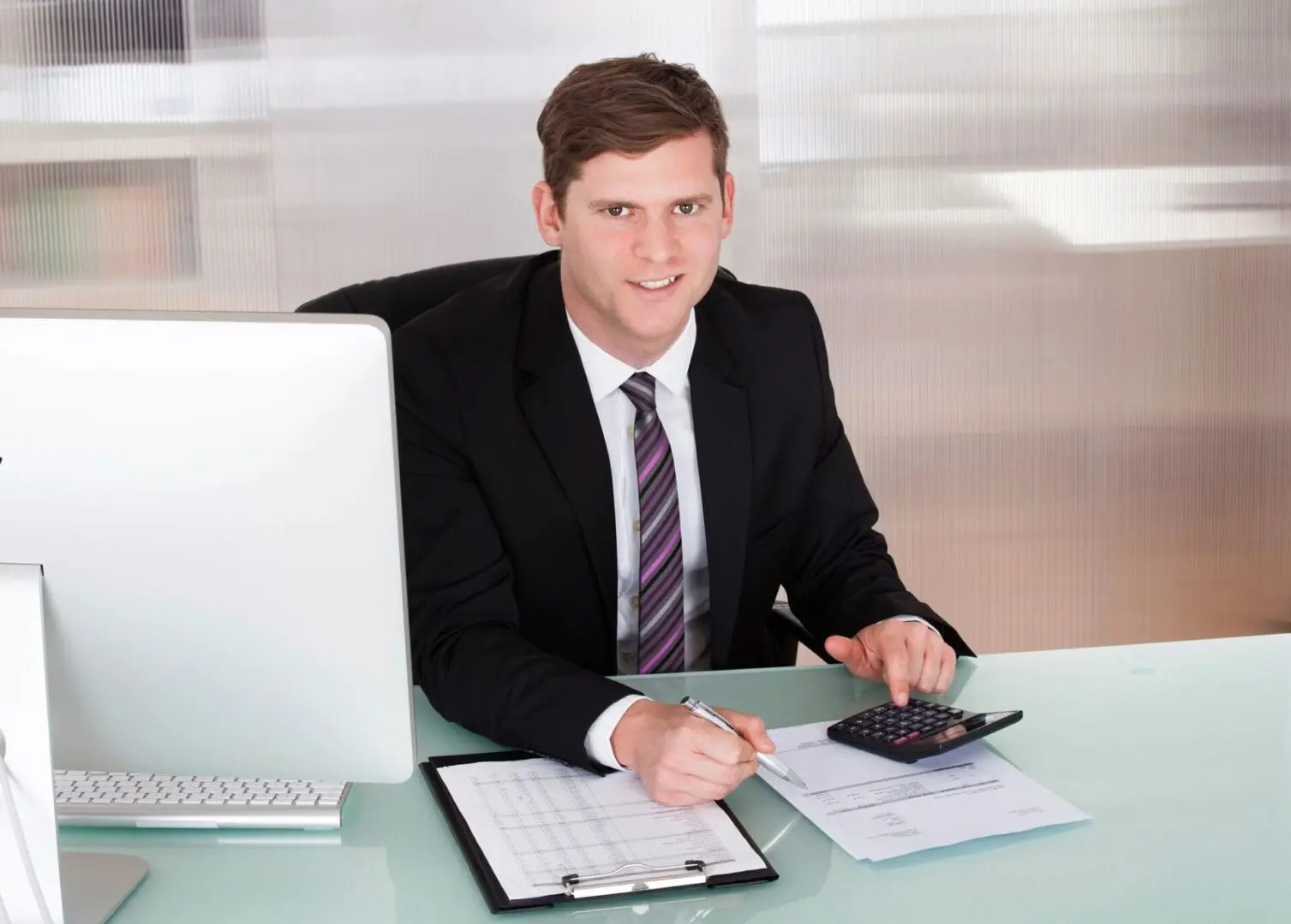 A man sitting at his desk with papers and a calculator.