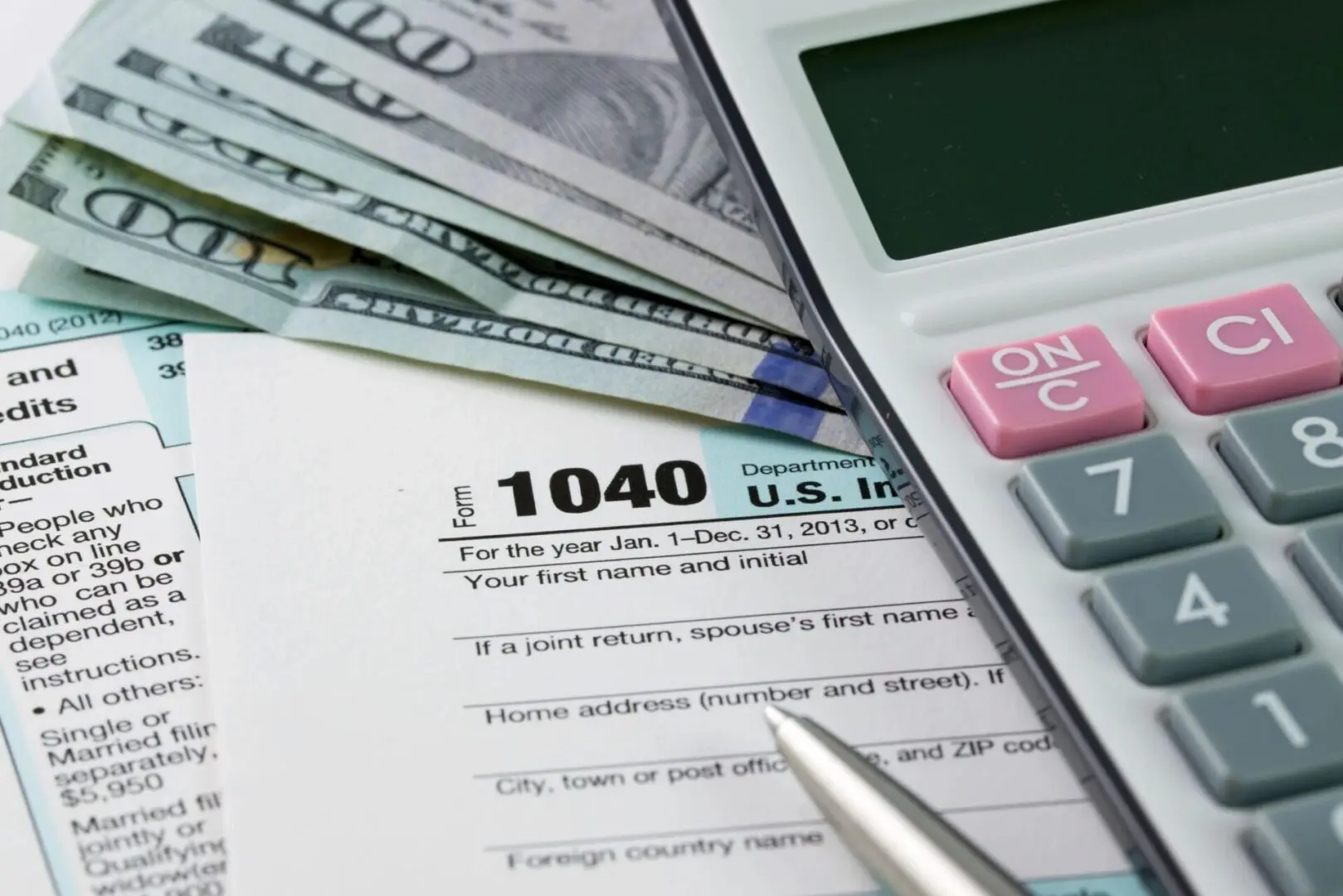 A calculator and some money sitting on top of a tax form.