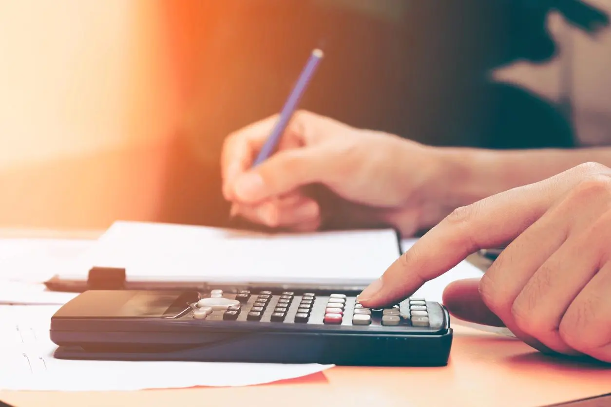 A person using a calculator and writing on paper.