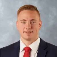 A man in a suit and tie standing next to a wall.